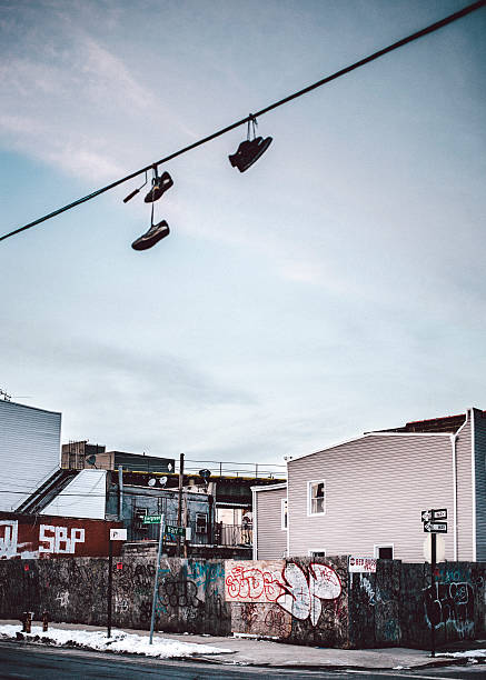 Pair of old dirty hightop sneakers hanging from the laces from a power line in the evening glow