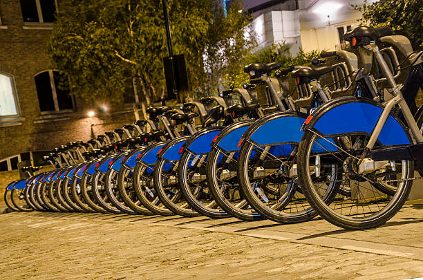 London with bicycles docks stations, England London City Bike Rental - Stock Image. Row of bikes for hire as part of a new scheme to encourage "pedal power" in the City of London. The aim is to reduce dependance on cars and thereby reduce London's polution, emission of greenhouse gases, conserve energy and of course to promote a healthier lifestyle. Sponsor's branding carefully removed. bicycle docking station stock pictures, royalty-free photos & images