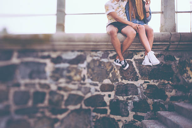 hipster par de piernas sentado sobre una pared de piedra - couple old fashioned hipster holding hands fotografías e imágenes de stock