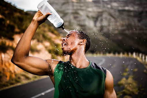African American athlete splashing water on his face to cool down after a good run for fitness and exercise