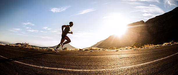 Panorama of a fit African American runner exercising outdoors Wide angle panorama of a runner exercising along a road with mountains in the background fish eye effect stock pictures, royalty-free photos & images