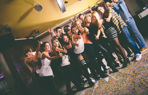 Group of friends posing for a photo giving a thumbs up sign in celebration of good times