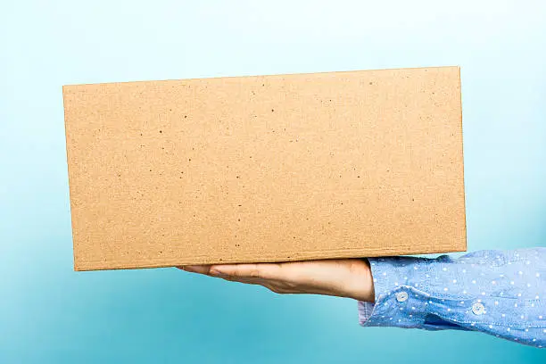 Photo of Woman weighing a cardboard box with her hand.