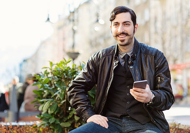 istock Young male with moustache using cell phone 470167542