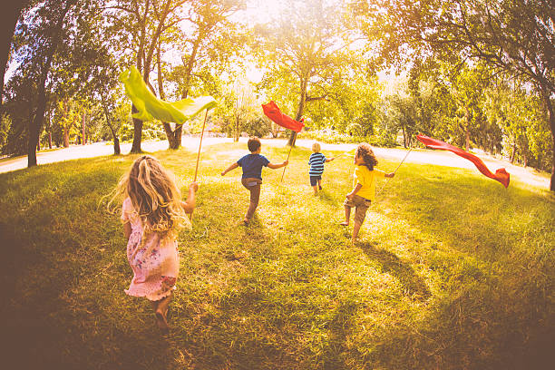 Friendly children playing in a park, running with colourful banners, in vintage style develop
