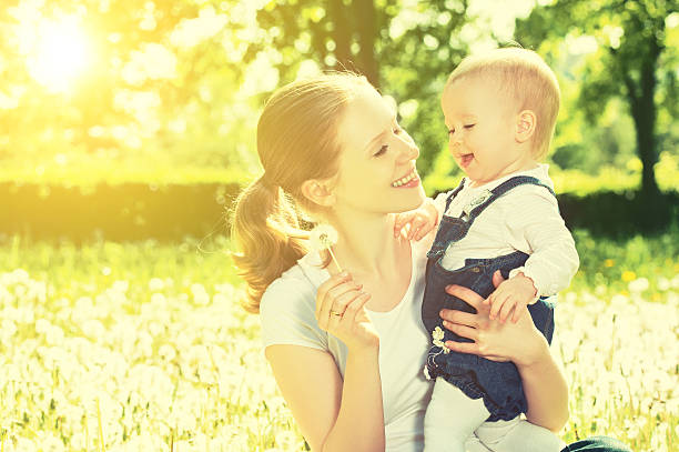 istock Smiling young mom and infant sit in a meadow on a sunny day 470168785