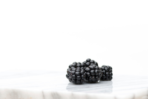 An arrangement of blackberries on a marble bench top with room of copy text at the top of the image.