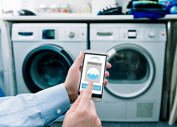 Telefone móvel com aplicativos usados para controle de máquinas de lavar - foto de acervo