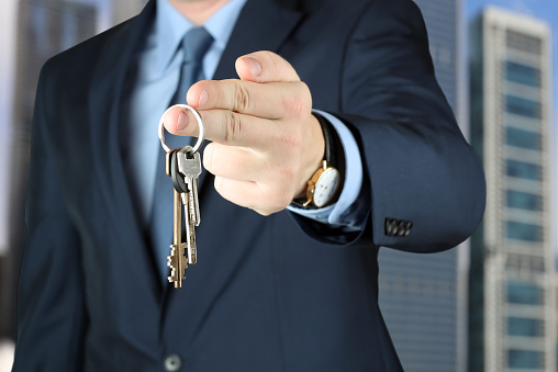 Cropped image of estate agent giving house keys outside