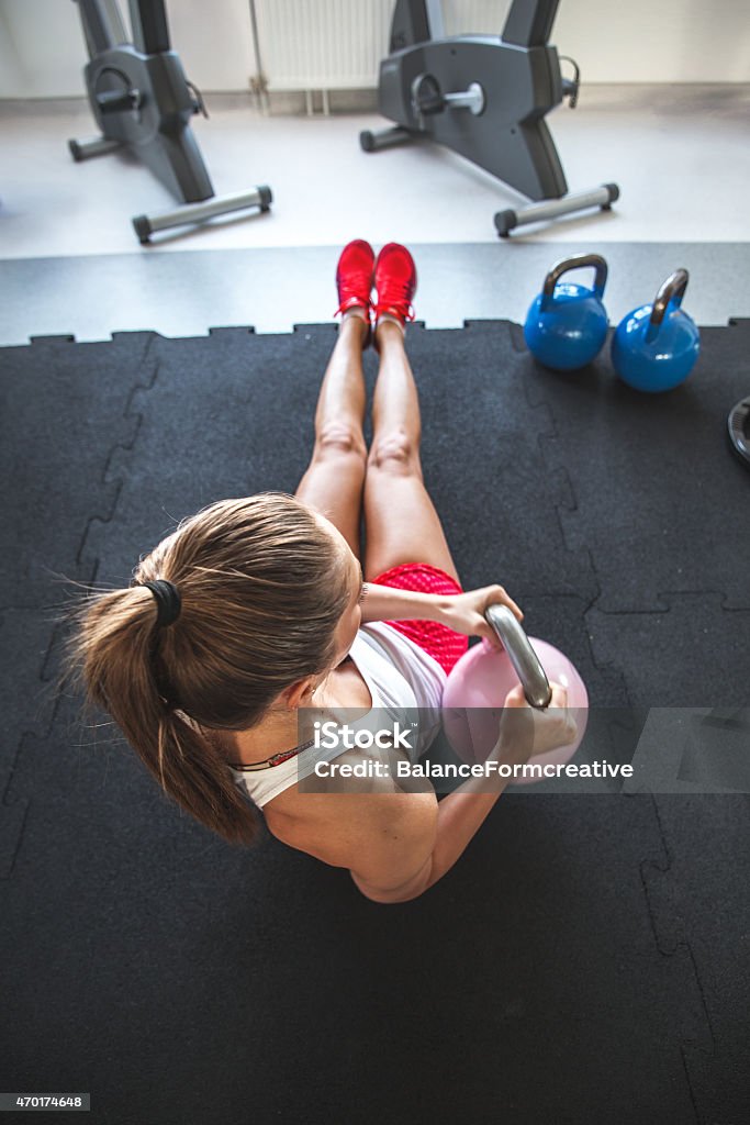 A woman doing a abs workout using a kettle bell weight Woman working on her abs with kettlebell.View from above. Exercising Stock Photo