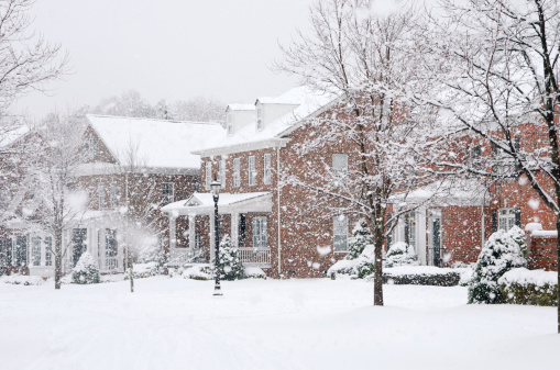 Traditional, brick homes are captured during a snow storm in this beautiful, Winter scene.