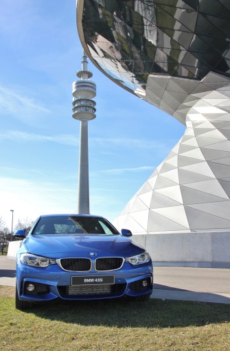 Munich, Germany - February 15, 2014: BMW 435 i before the new fantastic BMW Welt in Munich, in the background is the Olympic Tower. The photo was taken from public land. BMW is a German automobile manufacturer in the Premuimklasse the sporty cars built