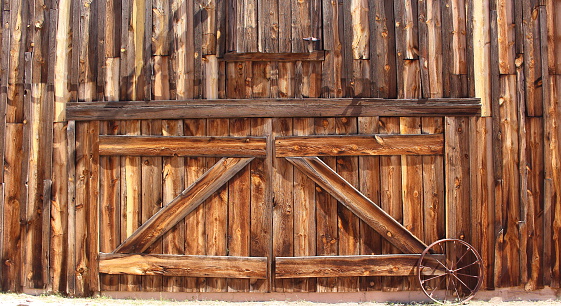 Front entrance of an old wooden farmhouse barn doors with metal wagon wheel 
