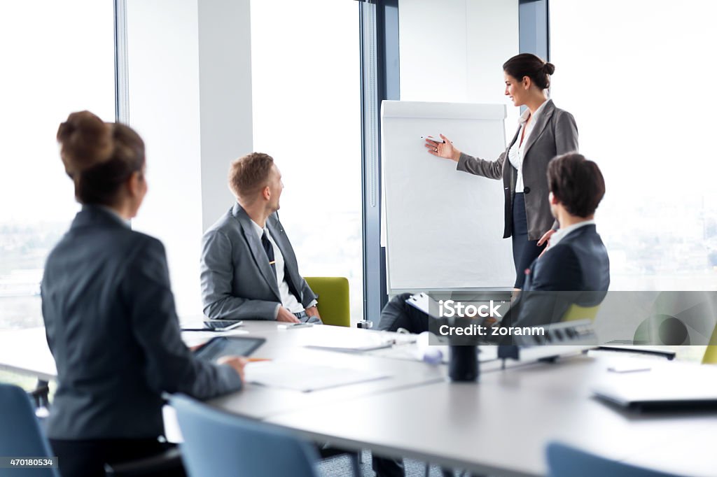 Business seminar with woman presenting on a white board Businesswoman holding presentation in board room, copy space 2015 Stock Photo