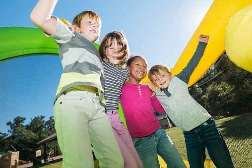 Four multi-ethnic children playing on bouncy castle