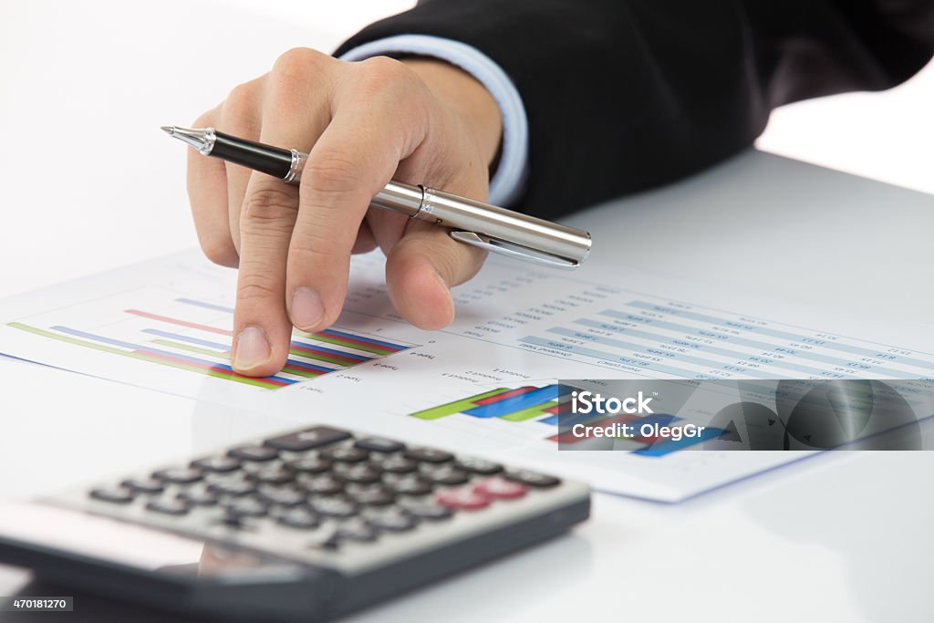 Close-up of hand holding pen with chart next to calculator Businessman analyzing investment charts at his workplace Defeat Stock Photo