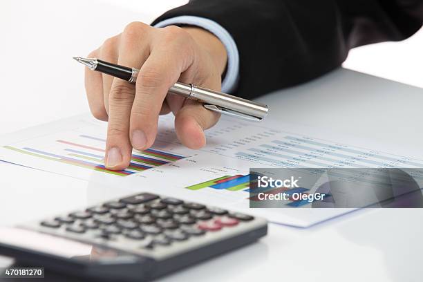 Closeup Of Hand Holding Pen With Chart Next To Calculator Stock Photo - Download Image Now