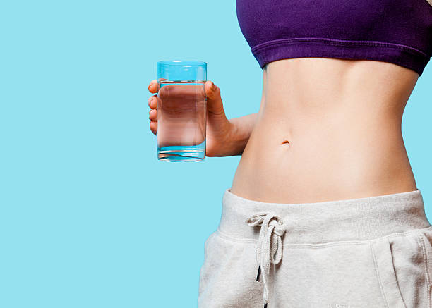 istock Woman showing her abs with water glass 470186460
