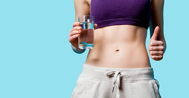 istock Woman showing her abs with water glass 470186462