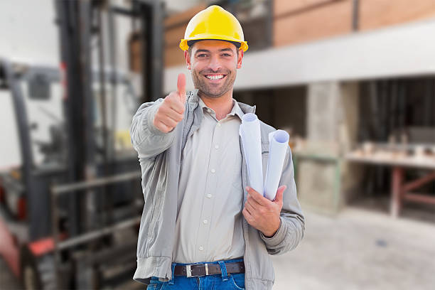 istock Man in yellow hard hat smiling and giving thumbs up 470190474