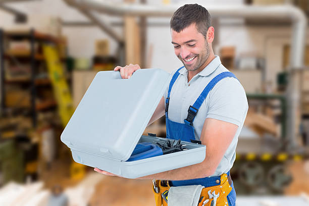 Happy repairman opening toolbox against workshop