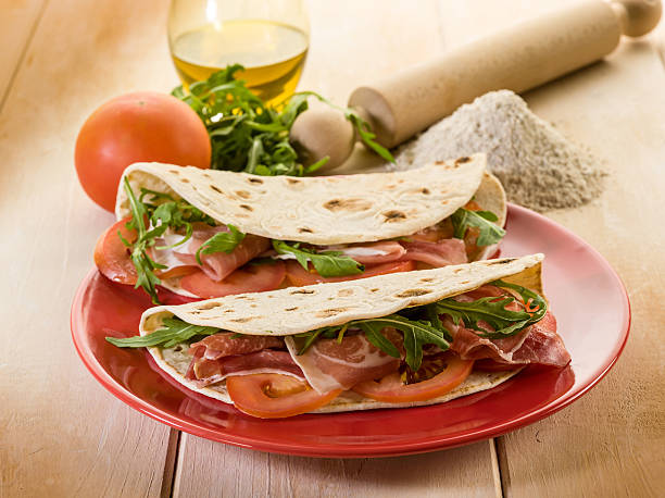 piadina con prosciutto e rucola, con pomodori, tipica italiana sandwich - piadina foto e immagini stock