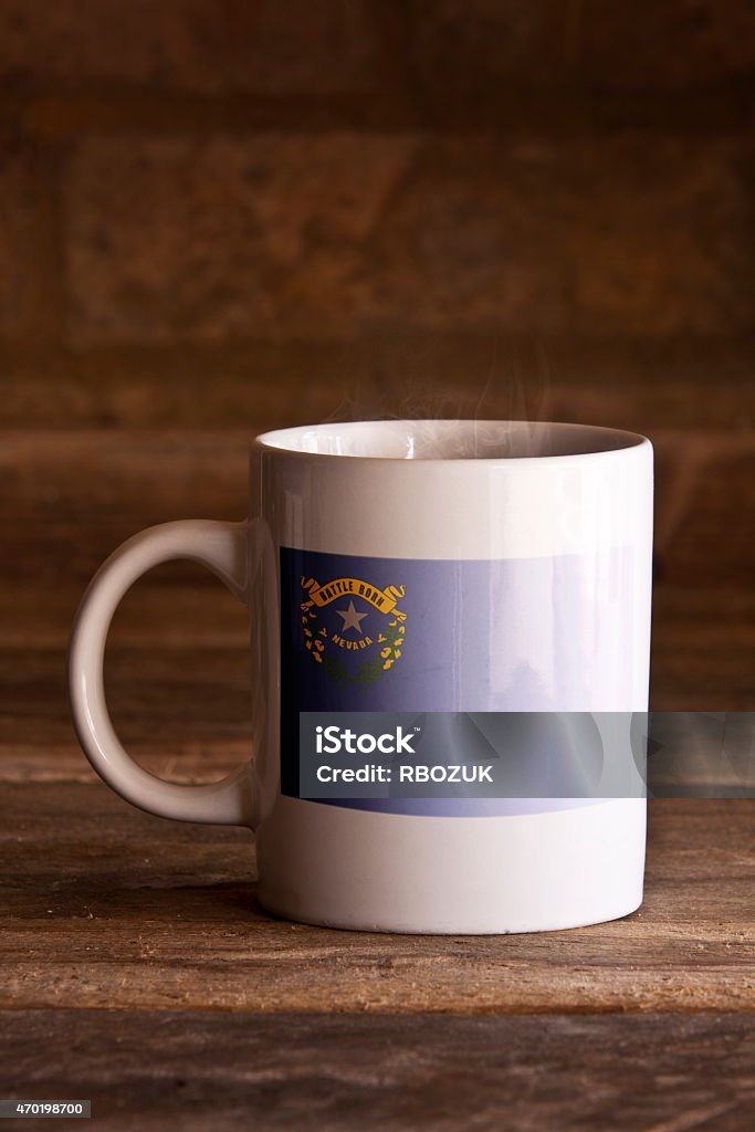 Nevada Mug on Wooden Background A macro shot of a white ceramic mug with a stenciled flag on the front, shot using natural daylight, on a wooden surface. 2015 Stock Photo