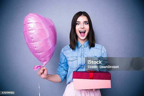 Amazed Woman Holding Balloon And Gift Box Stock Photo - Download Image Now - 2015, Adult, Anniversary