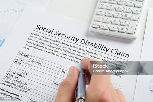 Person Hand With Pen Filling Social Security Disability Form Stock Photo - Download Image Now
