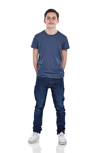 Full length portrait of cute young boy looking at camera smiling on white background