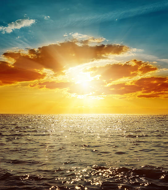 istock orange sunset in clouds over sea 470210474