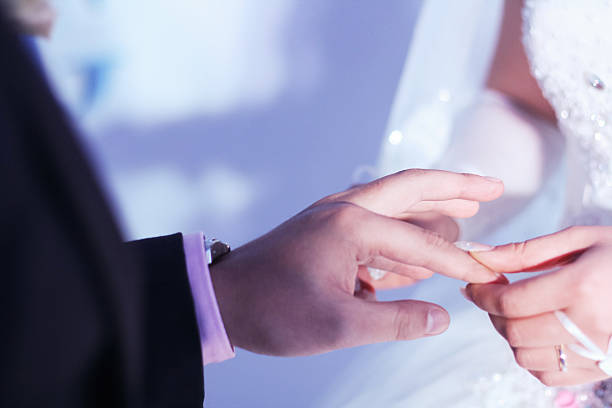 istock bride putting ring on groom's finger 470215096