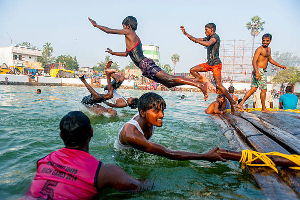 Mahabalipuram, India - March 14, 2014: Young men are playing on the bank of a pool in a small village close to Mahabalipuram, during a local Hindu Festival.