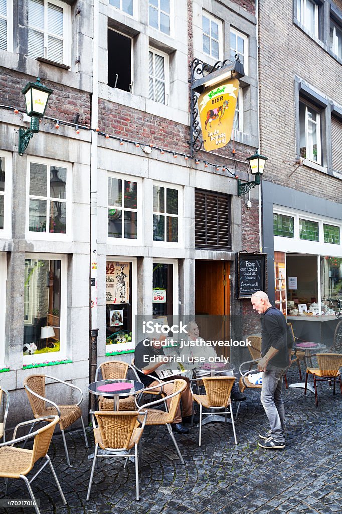 Caucasian senior men outside of bar and cafe in Maastricht Maastricht, The Netherlands - September 18, 2014: Capture of three caucasian senior men outside of bar and cafe in Maastricht in summer. Two men are sitting, one is reading newspaper. Third man is standing. Scene is in historical center. 2015 Stock Photo