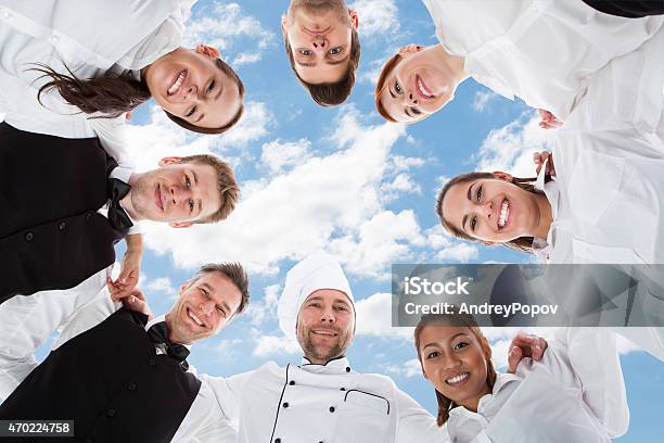 Happy Chef And Waiters Standing In Huddle Against Sky Stock Photo - Download Image Now