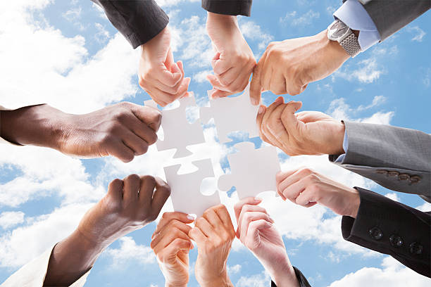 istock Multiethnic Business People Assembling Jigsaw Puzzle Against Sky 470225936
