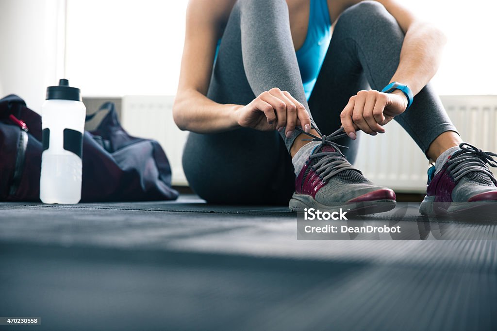 Worm's-eye view of gym floor and woman tying shoelaces Woman tying shoelaces at gym Bag Stock Photo