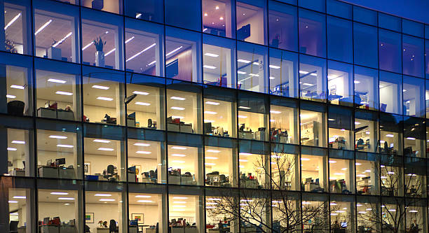Office block with lots of windows and office workers. London London, UK - December 19, 2014: Office block with lots of lit up windows and late office workers inside. City of London business aria in dusk. office window night stock pictures, royalty-free photos & images
