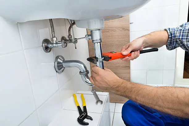 Close-up Of Male Plumber Fixing Sink In Bathroom