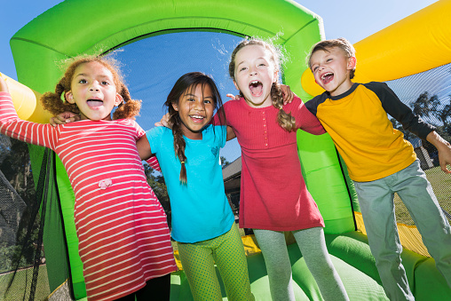 Four multi-ethnic children playing on bouncy castle