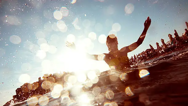 Silhouette of young woman splashing the water