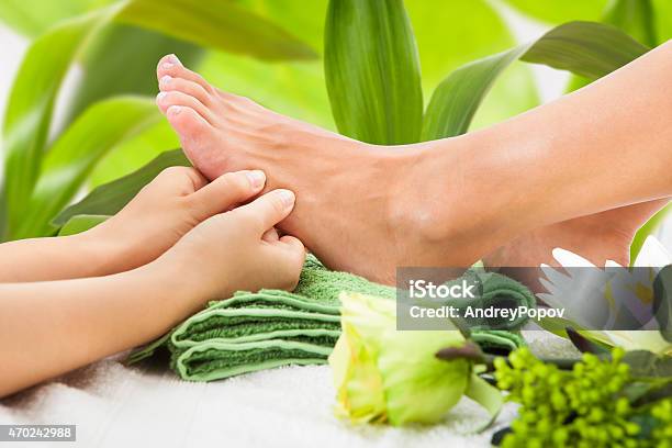 Masseuse Massaging Womans Foot Against Leaves Stock Photo - Download Image Now - 2015, Adult, Adults Only