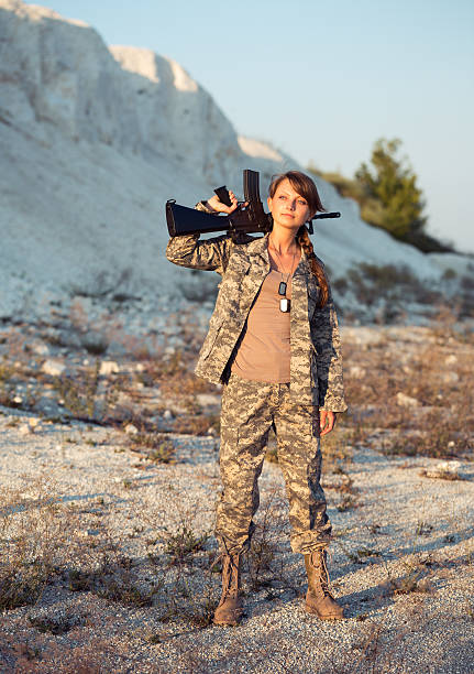 istock Young female soldier dressed in a camouflage with the gun 470245561