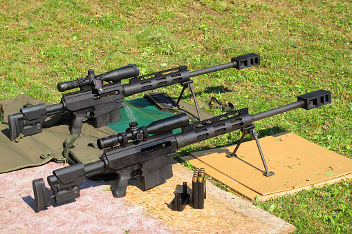 Two heavy sniper rifles .50 BMG caliber on shooting range.