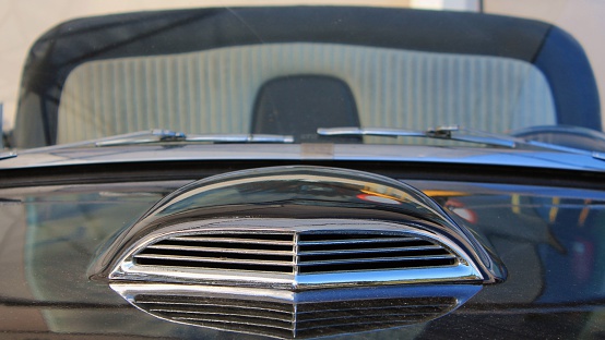 A close up of the front of an American classic car,looking up the bonnet at the air vent, up to the windscreen.