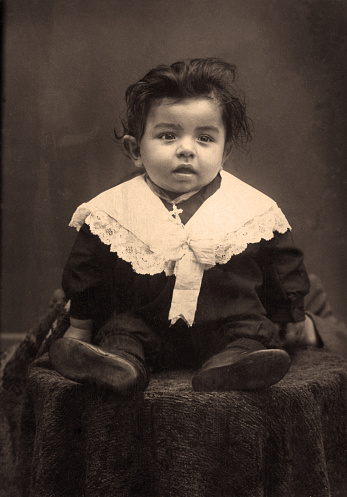 Circa 1931. Sepia vintage image of five year old little boy in typical period dress.