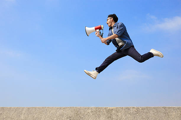 istock Man jumping in the air and shouting into a megaphone 470285358