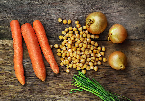 Group of vegetables onion carrot chickpeas and chive on  wood