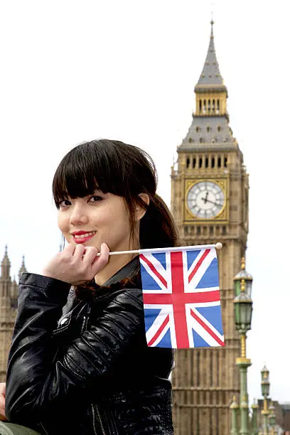 Girl holding UK flag in front of Bigben with smiel