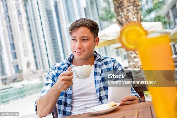 Young Man Drink Coffee And Using Tablet In Dubay Stock Photo - Download Image Now - 20-24 Years, 2015, 25-29 Years